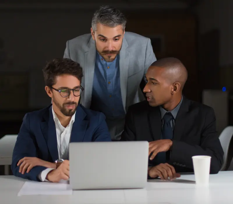 Three businessmen working together on a laptop.