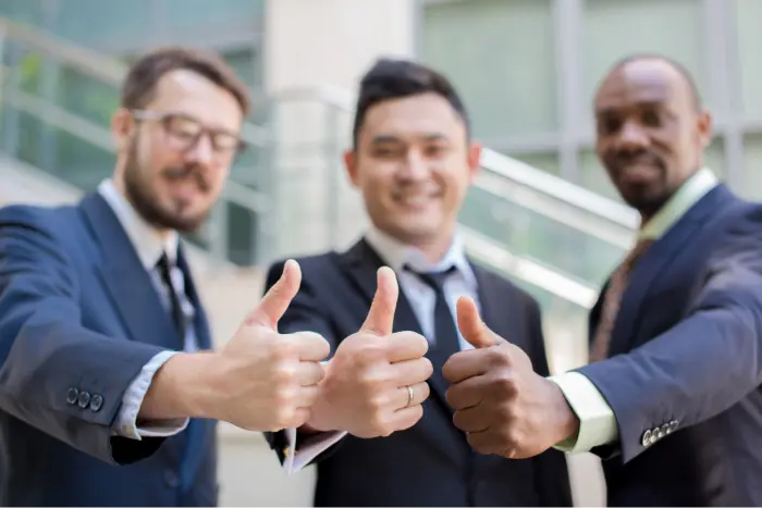 Three people showing the thumbs up sign to indicate success in their work.