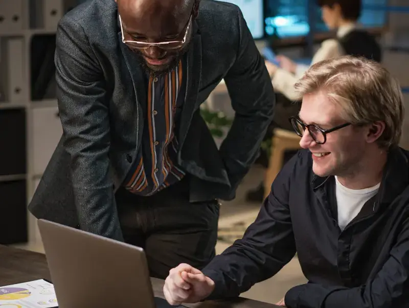 Two professionals monitoring a dashboard displaying IT service metrics, such as service uptime, service requests, and workflow automation.