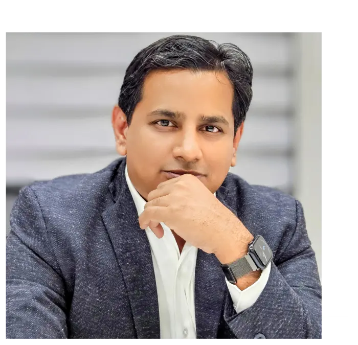 Mr. Manavalan Karunanithi, CEO of LMTEQ, wearing a white shirt and dark blazer, rests his chin on his hand in a thoughtful pose with a watch on his wrist.