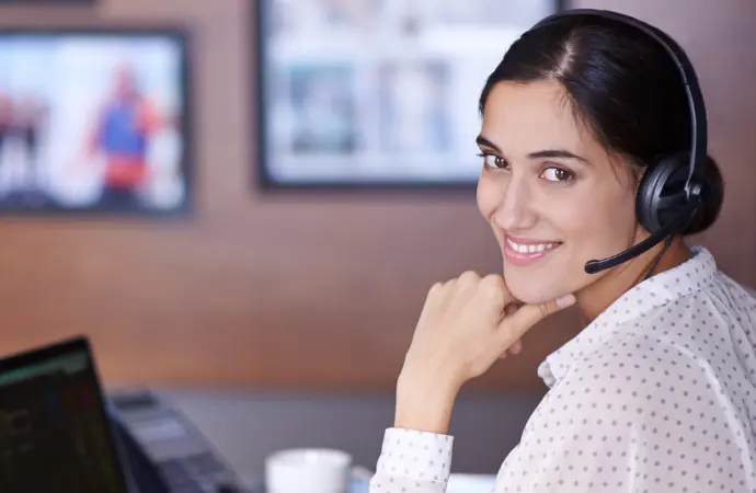 A woman in a headset smiles at the camera, representing customer service excellence in ServiceNow CSM.