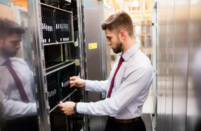 A man in a tie observes a server, representing ServiceNow Data Center Services and its technological infrastructure.